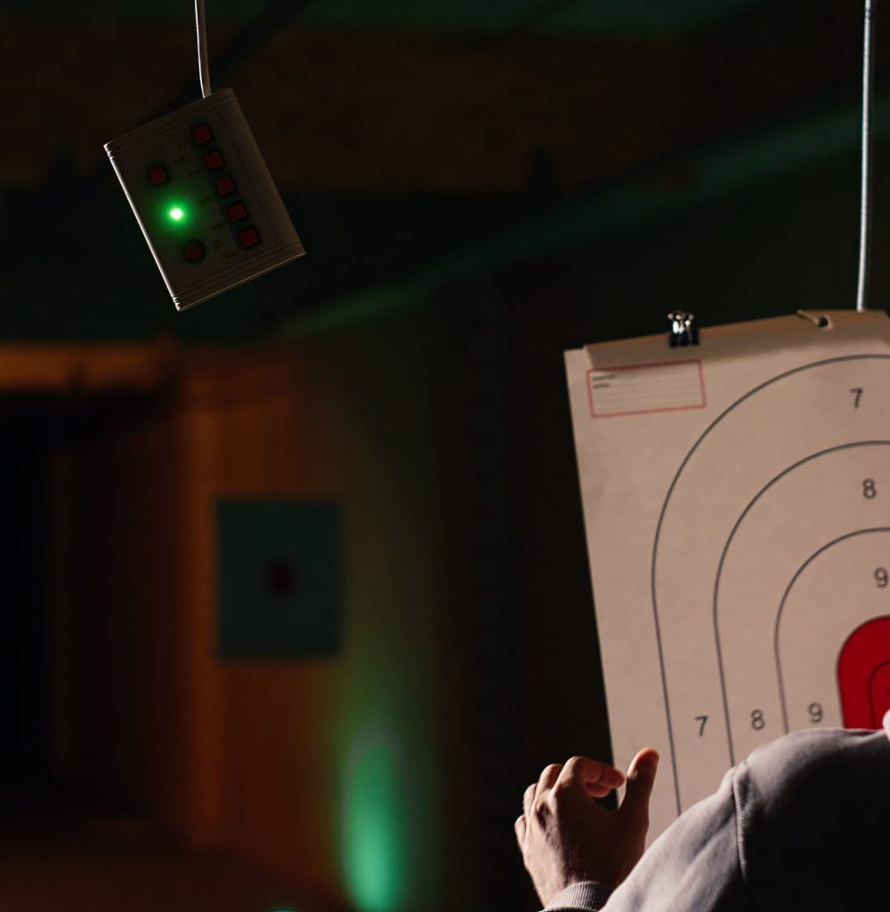 Group of friends in firing range doing recreational shooting activity with firearm, hitting bullseyes. People in shooting gallery training with handguns, sharpening skills, camera B